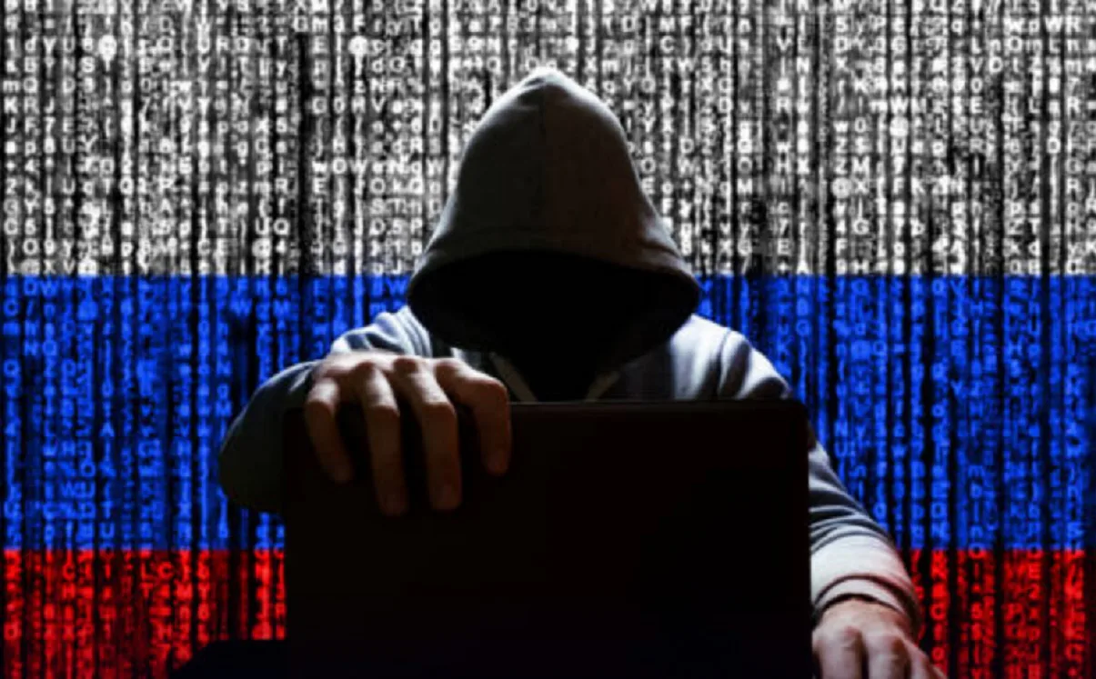 Російський хакер за ноутбуком на тлі прапора та бінарного коду